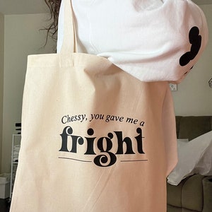Op de afbeelding: Een beige tote bag met zwarte tekst die "Chessy, you gave me a fright" luidt. De tekst is in een vetgedrukt, decoratief lettertype.