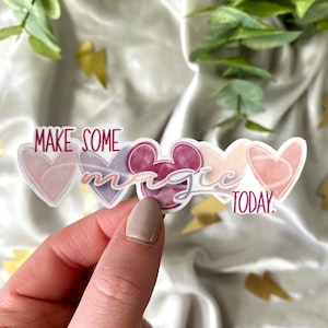 May include: A sticker with a pink, purple, and red watercolor design. The sticker features a Mickey Mouse head, hearts, and the text "Make some magic today."