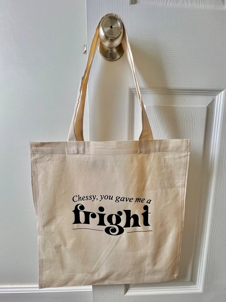 Op de afbeelding: Een beige canvas draagtas met zwarte tekst die "Chessy, you gave me a fright" zegt.