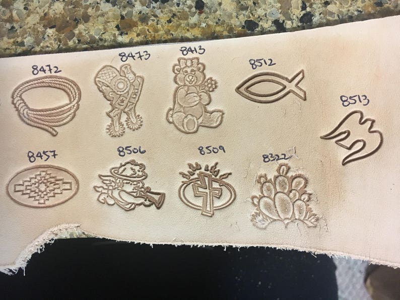 May include: A close-up of a leather surface with various designs stamped into it. The designs include a rope circle, a bear, a fish, a bird, a cross, a cactus, and a cherub. Each design is labeled with a number.