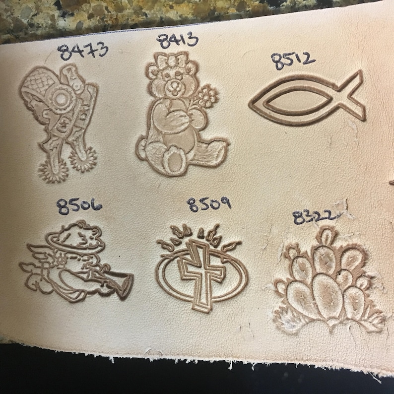 May include: A close-up of a leather sheet with various embossed designs. The designs include a teddy bear, a fish, a cross, a bowling pin, and an angel. Each design is labeled with a number.