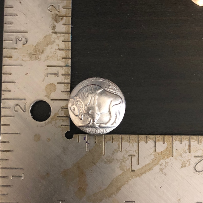 Puede incluir: Una moneda de n&iacute;quel de cinco centavos de b&uacute;falo estadounidense de color plateado con las palabras "United States of America" y "Five Cents" inscritas en la moneda.