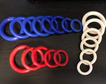 May include: A set of colorful plastic rings in blue, red, and white. The rings are arranged in size order, with the largest ring at the top and the smallest ring at the bottom.