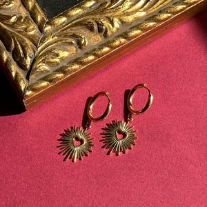 Flaming heart pendants on gold hoop earrings