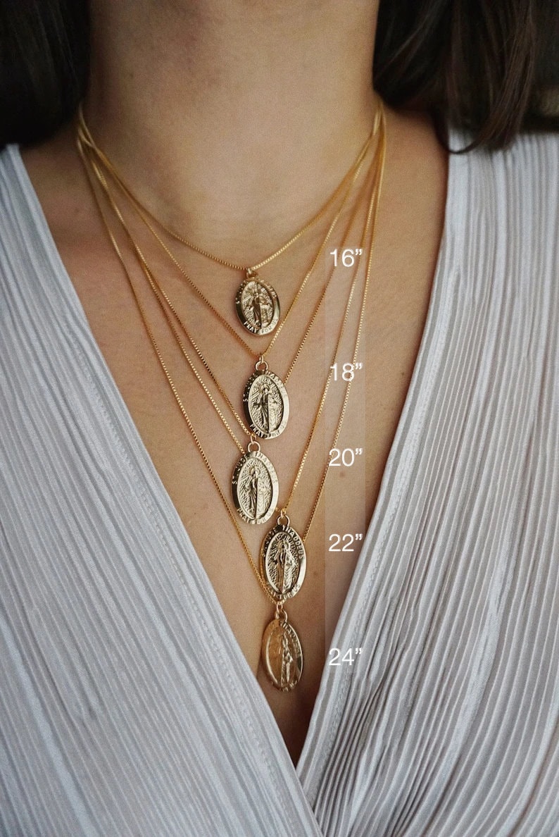K&ouml;nnte beinhalten: F&uuml;nf goldene Kettenhalsb&auml;nder mit jeweils einem religi&ouml;sen Anh&auml;nger. Die Ketten sind 40, 45, 50, 55 und 60 cm lang.