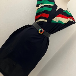 May include: A vintage black dress with a colorful striped bodice and a matching belt. The bodice features horizontal stripes in red, green, white, purple, and black. The belt has a circular buckle with rainbow-colored accents.
