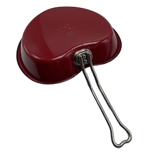 Puede incluir: Sartén roja en forma de corazón con mango plateado. La sartén tiene un acabado liso y brillante.