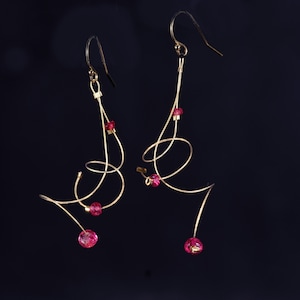 May include: A pair of gold earrings with a delicate, swirling design and pink crystal accents.