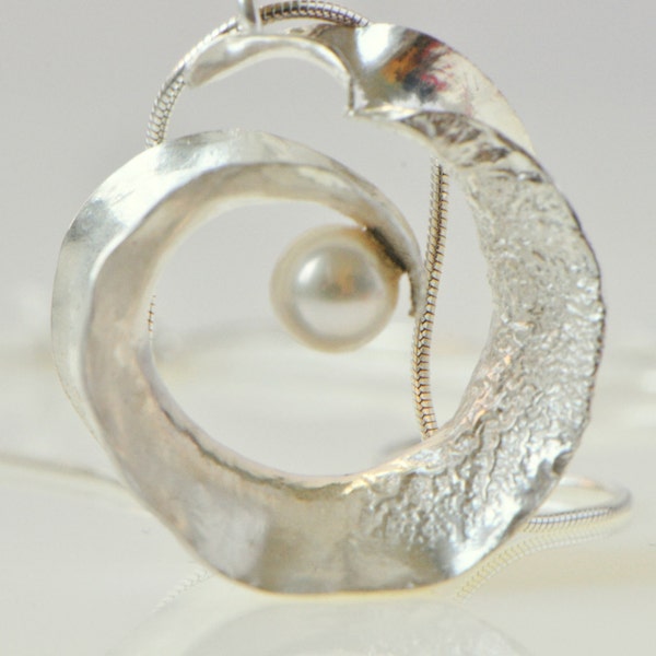 Anticlastic three-dimensional spiral pendant in sterling silver with white freshwater pearl