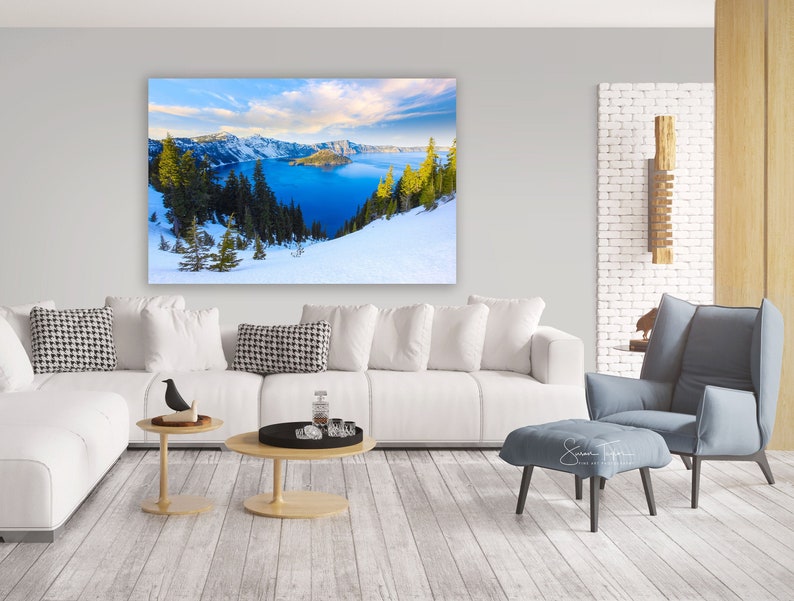 May include: A panoramic view of Crater Lake in Oregon, with snow-capped mountains in the background and a blue lake in the foreground. The lake is surrounded by evergreen trees and a snowy landscape.