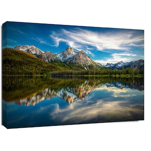 May include: A scenic landscape photograph of a mountain range reflected in a still lake. The mountains are snow-capped and the sky is blue with white clouds. The lake is a deep blue color and the water is calm.