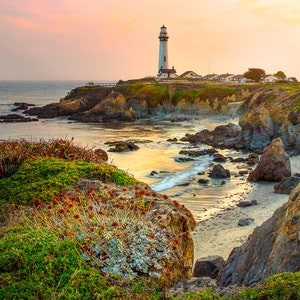 May include: A white lighthouse stands on a rocky cliff overlooking a calm ocean at sunset. The sky is a soft pink and purple, and the water is a shimmering gold.