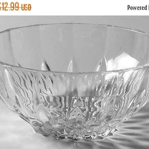 May include: A clear glass bowl with a textured, rippled design. The bowl is empty and has a wide, shallow shape.