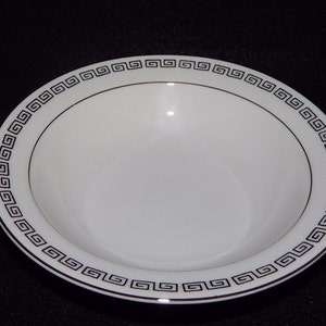 May include: White ceramic bowl with a black and gold Greek key design around the rim.
