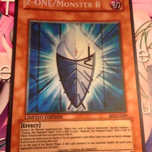 May include: A Yu-Gi-Oh! trading card featuring the character Z-ONE/Monster B. The card has a brown border and a central image of a blue and white shield-like design. Text includes "LIMITED EDITION" and card effects.