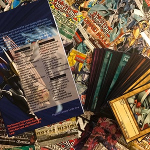 Puede incluir: Una colecci&oacute;n de cartas de intercambio de Yu-Gi-Oh!, que incluye un paquete de refuerzo, una caja de mazo y un conjunto de cartas con el monstruo Alpha the Magnet Warrior. Las cartas est&aacute;n dispuestas sobre una mesa con otros productos de Yu-Gi-Oh! en el fondo.
