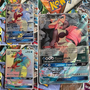 May include: A holographic Pokemon trading card featuring Milotic GX, a pink and blue water-type Pokemon with a large, flowing tail. The card has a silver background and features the text "Mystic Scale", "Hypno Splash", and "Summer Days GX".