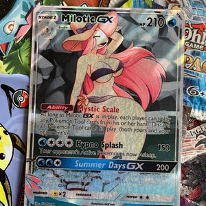 May include: A holographic Pokemon trading card featuring Milotic GX, a pink and blue water-type Pokemon with a large, flowing tail. The card has a blue background with white text and stars. The card's text includes the Pokemon's name, HP, abilities, and attacks. The card is in excellent condition.
