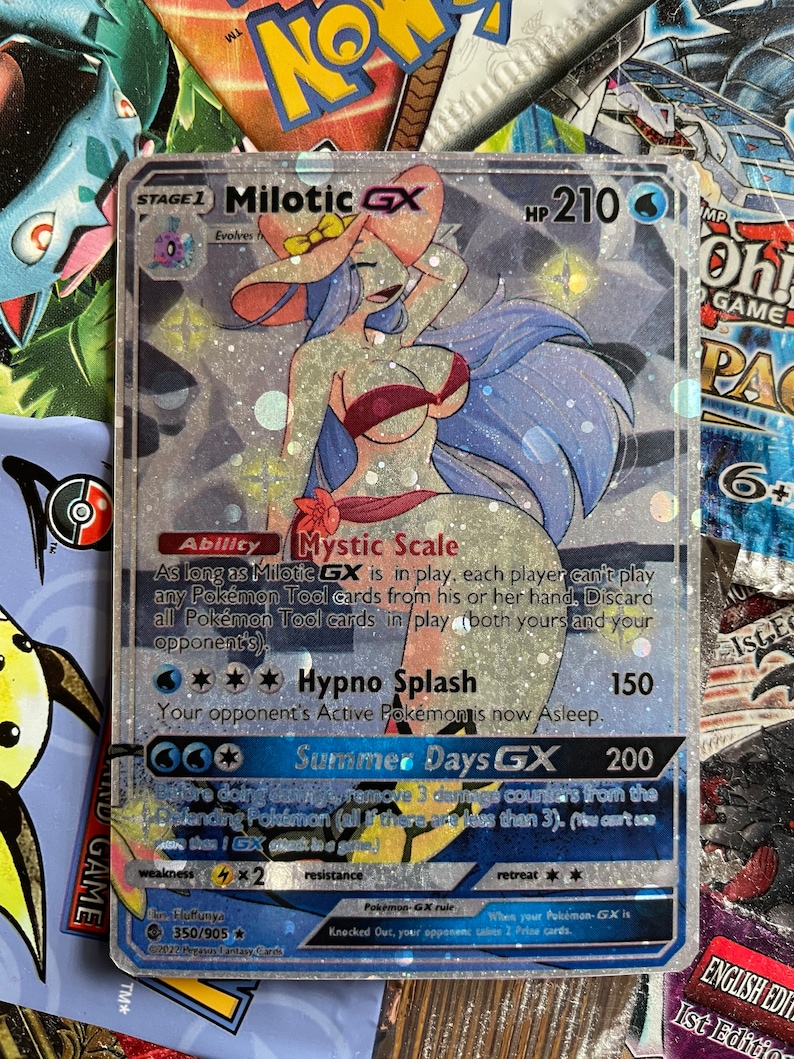 May include: A holographic Pokemon trading card featuring Milotic GX, a water-type Pokemon with a blue and pink color scheme. The card has a silver background with glitter and features the text "Mystic Scale" and "Hypno Splash".