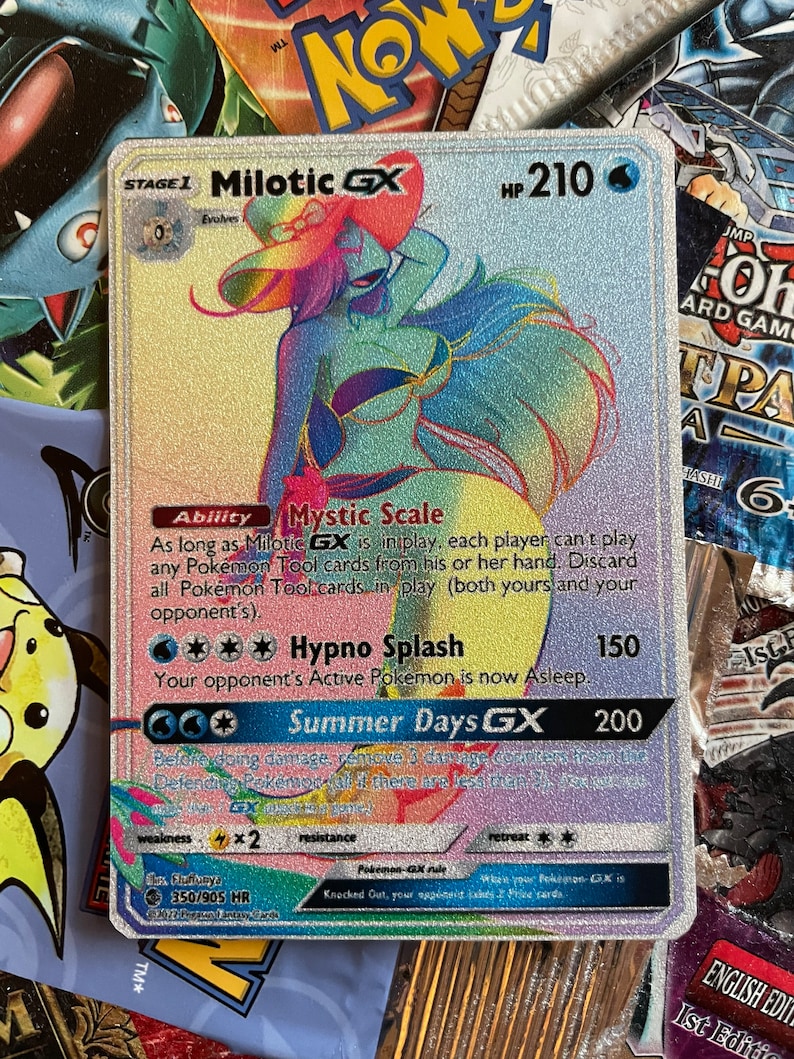 May include: A holographic Pokemon trading card featuring Milotic GX, a water-type Pokemon with a pink, blue, and yellow color scheme. The card has a HP of 210 and features the abilities Mystic Scale and Hypno Splash. The card also has a GX attack called Summer Days GX.