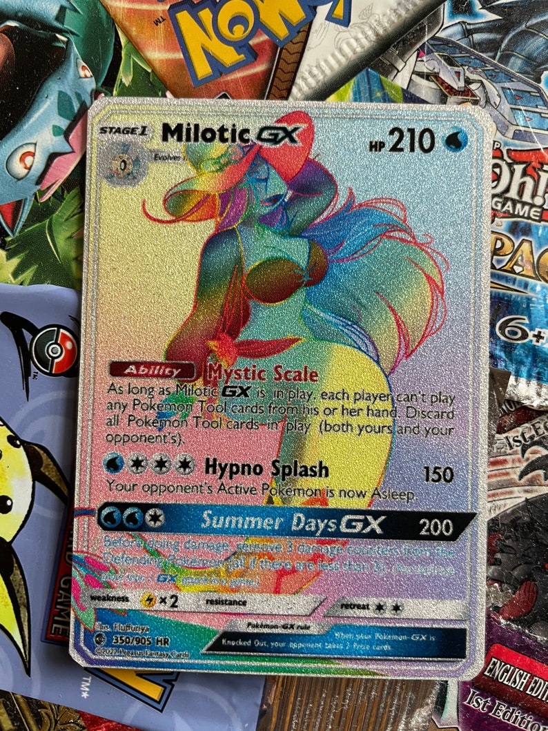 May include: A holographic Pokemon trading card featuring Milotic GX, a water-type Pokemon with a pink and blue color scheme. The card has a HP of 210 and features the abilities Mystic Scale and Hypno Splash. The card also has a GX attack called Summer Days GX.