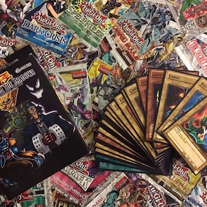 Op de afbeelding: Een verzameling Yu-Gi-Oh! trading cards, inclusief booster packs en individuele kaarten. De booster packs hebben verschillende thema's, zoals "Dark Crisis", "Speed Ruler" en "The Secret Forces". De individuele kaarten omvatten "Archfiend Mirror", "Barox" en "Castle".