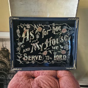 May include: Framed artwork with the text "As for Me and My House we will Serve the Lord" in a decorative font. The black background is accented with floral designs and a gold-toned frame.