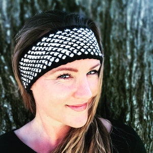 May include: A woman with long blonde hair is wearing a black and white crocheted headband. The headband has a geometric pattern.