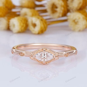 Pode incluir: Um delicado anel de ouro rosa com um diamante em forma de marquise engastado em um design de inspiração vintage. A banda apresenta detalhes florais intrincados.