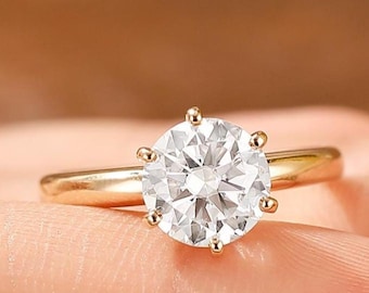 May include: A gold engagement ring with a large, round, clear diamond.