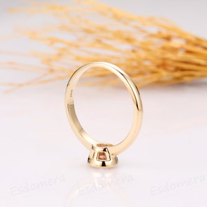 A gold ring with a small, round, light brown gemstone set in the center. The ring is simple and elegant, with a smooth band.