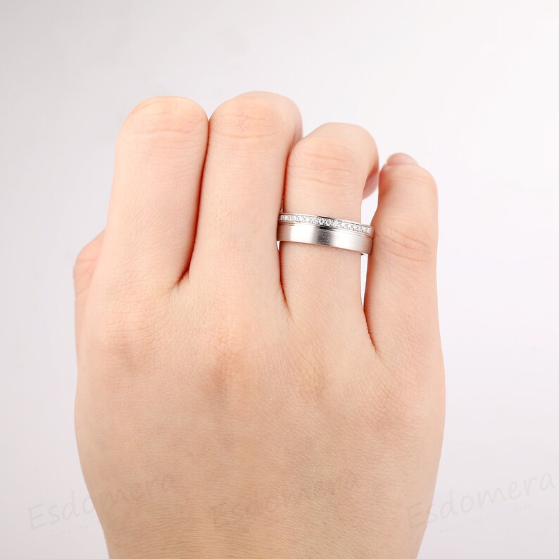 May include: A silver wedding band with a row of small diamonds set in the band.