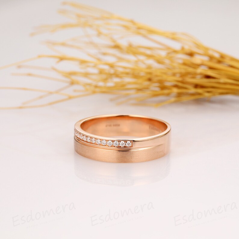 May include: A rose gold wedding band with a row of small diamonds set into the band.