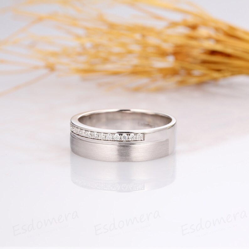 May include: A silver wedding band with a row of small diamonds set into the band.