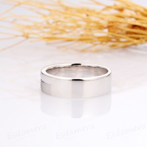 May include: A simple, silver wedding band with a flat, polished surface.