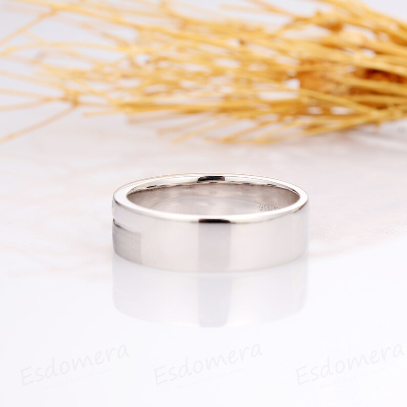 May include: A simple, silver wedding band with a flat, polished surface.