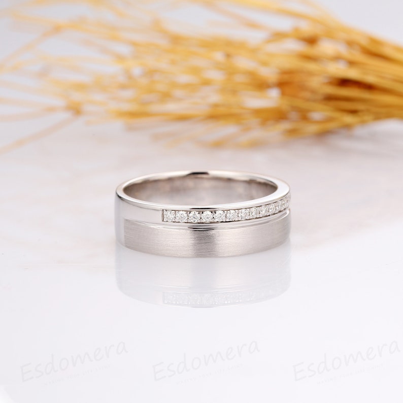May include: A silver wedding band with a row of small diamonds set into the band.