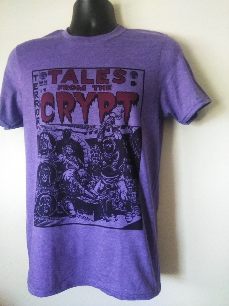 May include: Purple t-shirt featuring a graphic print of a comic book cover with the text "Tales from the Crypt" and a scary illustration.