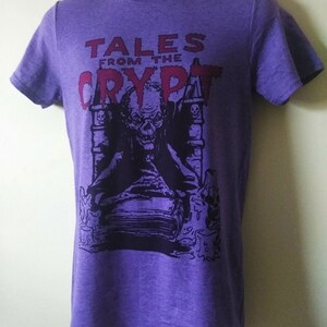 May include: Purple t-shirt with a black and white graphic of a monster from Tales from the Crypt. The text "Tales from the Crypt" is in red.