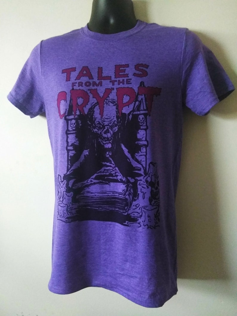 May include: Purple t-shirt with a black and white graphic of a monster from Tales from the Crypt. The text "Tales from the Crypt" is in red.