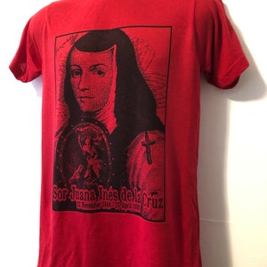 May include: Red t-shirt with a black and white image of Sor Juana In&eacute;s de la Cruz, a Mexican poet and nun. The image includes the text "Sor Juana In&eacute;s de la Cruz 12 November 1648 - 17 April 1695".