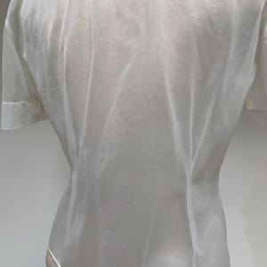 May include: A white sheer blouse with a button-up front and short sleeves.