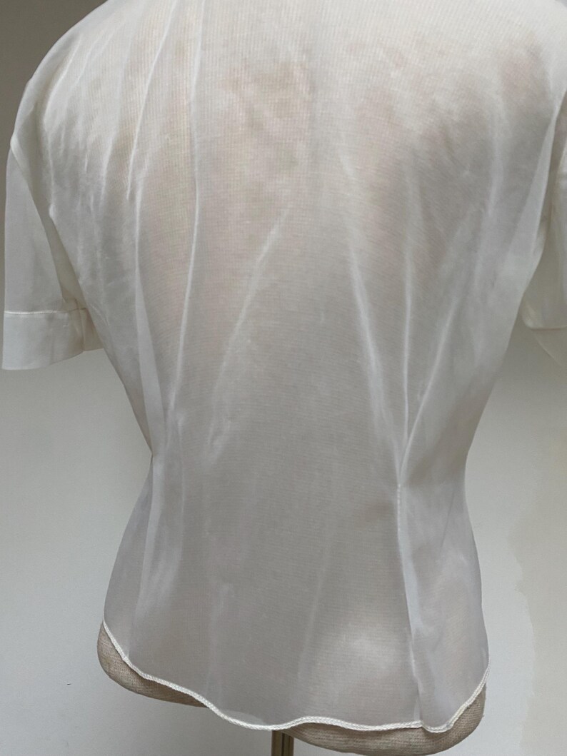 May include: A white sheer blouse with a button-up front and short sleeves.