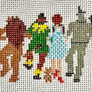 May include: Needlepoint canvas depicting characters from The Wizard of Oz. The Lion, Scarecrow, Dorothy, and Tin Man are shown in a colourful, cross-stitch style. The figures are set against a neutral background, showcasing the iconic characters.
