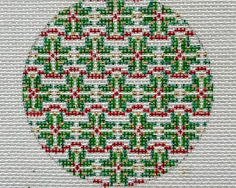 May include: A close-up of a circular cross-stitch design featuring a repeating pattern of green, red, and gold squares. The design is stitched on a white fabric background.