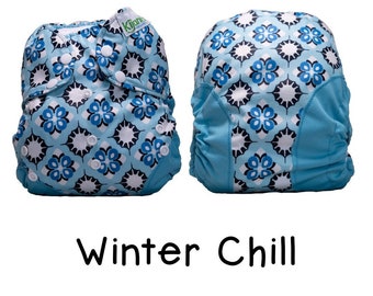 May include: A blue and white patterned cloth diaper with a green "Kijam" logo. The diaper is folded and ready to use. The diaper is called "Winter Chill".