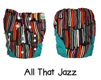 May include: A colorful cloth diaper with a teal trim and a black, white, red, and orange striped pattern. The diaper has the text "Kilian" printed on it. The diaper is called "All That Jazz".