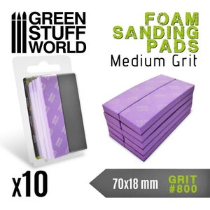 Puede incluir: Un paquete de 10 almohadillas de lijado de espuma de color púrpura, etiquetadas como "Granulo medio" y "GRIT #800". Las almohadillas miden 70x18 mm y están empaquetadas en una bolsa de plástico transparente con una tarjeta de encabezado que dice "GREEN STUFF WORLD".