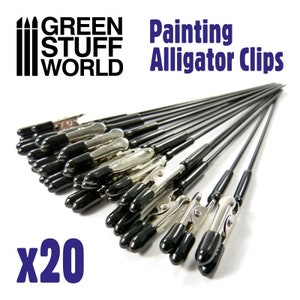 May include: A set of 20 black alligator clips with black rubber tips. The clips are attached to long, thin black rods. The clips are used for holding items in place while painting.