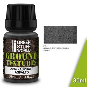 May include: A 30 ml bottle of Green Stuff World Ground Textures Asphalt. The bottle is black with a green label that says "Green Stuff World Ground Textures 2794 - Asphalt Asfalto". The label also has a small image of three trees. The bottle is sitting on a brown surface. A small sample of the asphalt texture is shown in the upper right corner of the image.